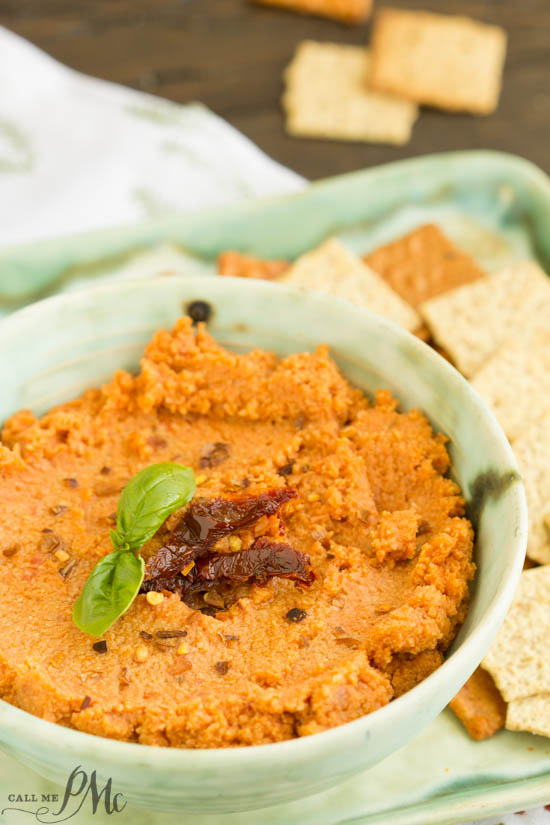 Sun Dried Tomato Hummus Recipe is creamy, spicy, and has a nice earthy flavor from the sun-dried tomatoes. This easy recipe comes together quickly and will become your go-to recipe! Reddish dip in a bowl.