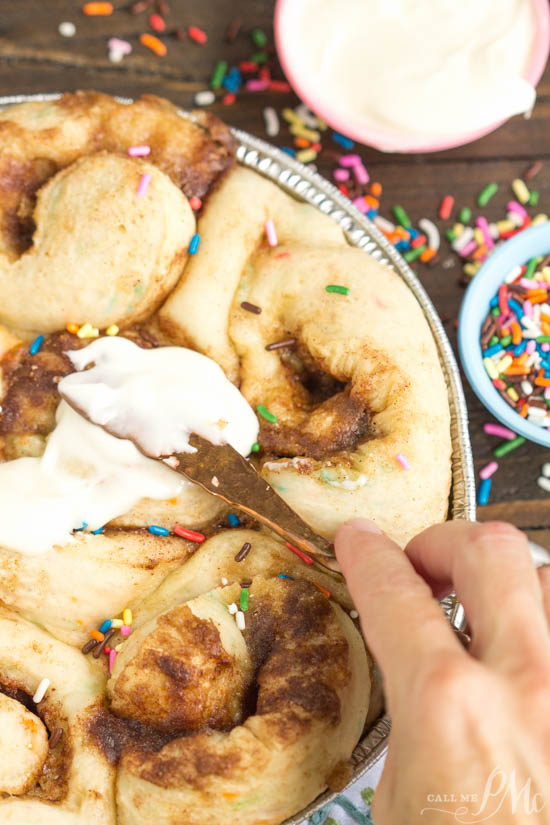 Tender and fluffy Birthday Cake Cinnamon Rolls is like having birthday cake for breakfast! Fun, festive, easy to make, and they taste heavenly! This recipe is definitely one you want to have on your breakfast roster! Frosting a pan of cinnamon rolls.