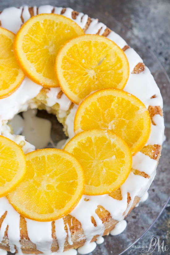 An orange juice pound cake with orange slices on top.