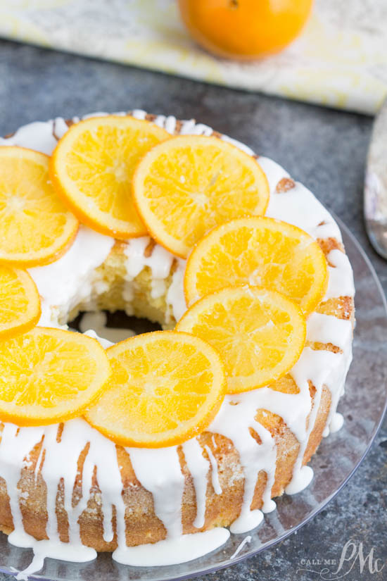 A Bundt cake with orange slices on top, made with orange juice.