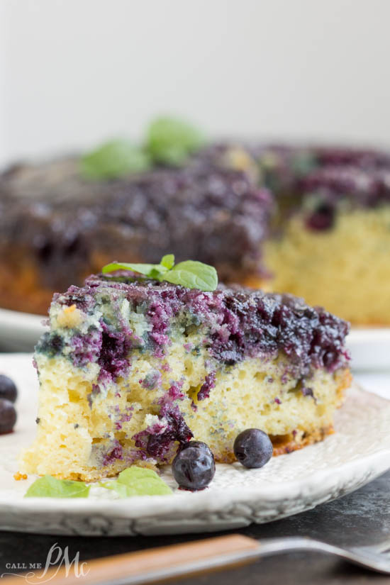 Homemade Blueberry Upside-down Cake is unbelievably good. Blueberries and a caramel glaze ooze down into the tender yellow cake making it moist and decadent. This cake recipe has quickly become one of my all-time favorites! Slice of cake on a plate.