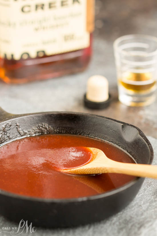 wooden spoon in a cast iron skillet of whiskey bbq sauce.
