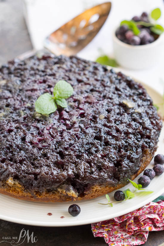 Homemade Blueberry Upside-down Cake is unbelievably good. Blueberries and a caramel glaze ooze down into the tender yellow cake making it moist and decadent. This cake recipe has quickly become one of my all-time favorites! Upside down cake on a plate.