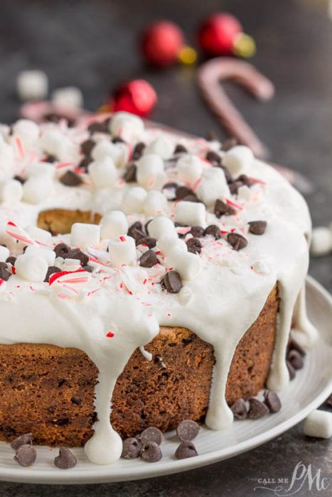 A Candy Cane Chocolate Chip Pound Cake with white icing, mini marshmallows, crushed peppermint, and chocolate chips on top, displayed on a white plate.
