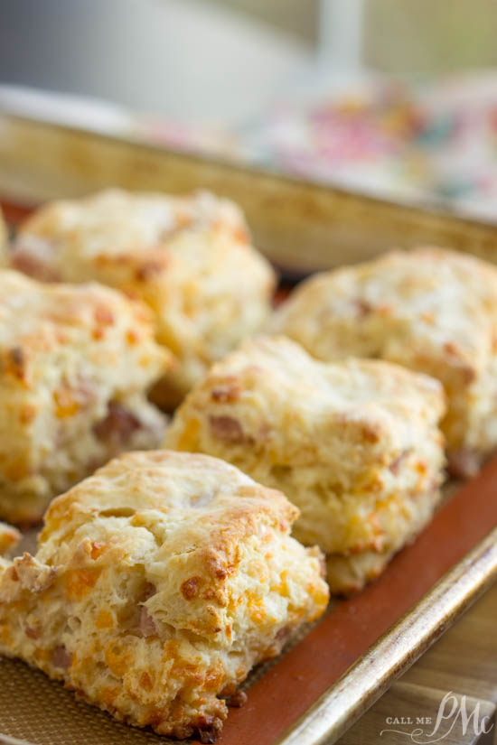 Scones. ham. cheese. recipe. breakfast. Buttery and flaky these homemade Cheesy Ham buttermilk biscuits are adorned with ham and cheddar cheese. Seriously amazing! This southern style breakfast with homemade biscuits and country ham and gooey cheese is the perfect hearty breakfast! These biscuits are buttery, savory, and a well-deserved treat! Buttermilk biscuits with a golden crust rest perfectly on the baking tray.