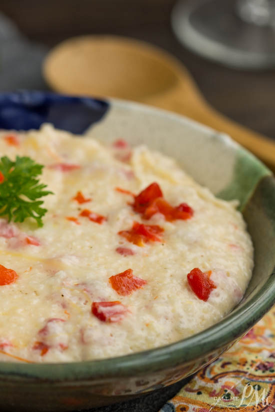 Bowl of creamy food with red peppers.