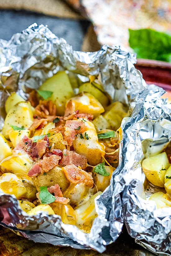 These easy Campfire Potato Foil Packs are flavorful, loaded potatoes cooked inside foil packs, then topped with melty cheese and bacon. This quick, delicious, and nourishing side dish recipe is great while camping or in the oven for any occasion! No pans to wash afterward makes the cook happy too!