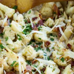 Sautéed Cauliflower and bacon oven baked in a cheesy creamy garlic sauce topped with bubbling mozzarella and parmesan cheese!