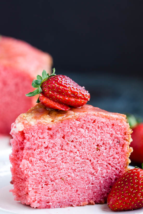 Indulge in a slice of strawberry cake on a plate with fresh strawberries.
