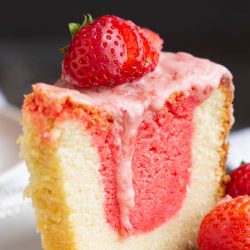 A slice of strawberry pound cake drizzled with cream.