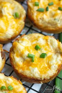 Close-up of Crack Chicken Biscuit Bites, cheesy bread cups topped with chopped green onions, resting on a wire cooling rack.