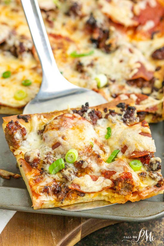 Pizza in a pan with one slice being served on a spatula.