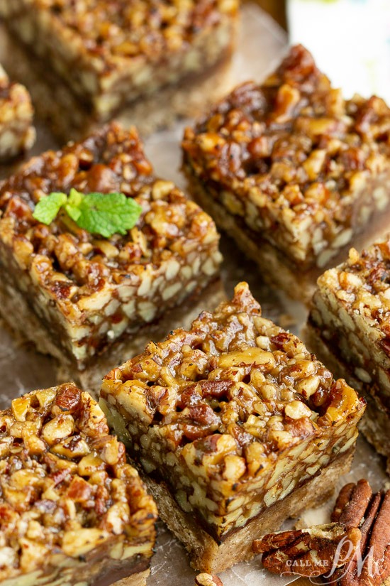 Pecan bars on a baking sheet with a mint sprig.