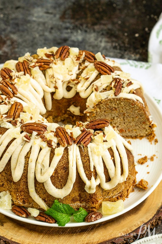 This incredibly tender and moist Blue Ribbon Roasted Carrot Pound Cake with Pineapple Mascarpone Frosting Recipe is the best carrot cake you'll ever make! A cake topped with frosting, garnished with pecans, rests invitingly on a white plate.