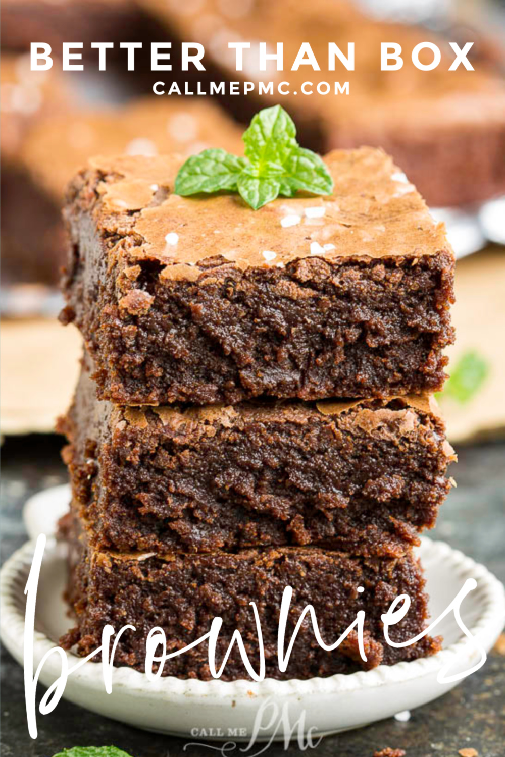 How do I make clean-cut brownies? Itโs important to cut them when theyโre completely cool, otherwise youโll have an ooey gooey mess and brownies that lose their shape. Take the biggest knife you have, preferably one thatโs the length of the entire pan of brownies. Then just cut straight down in one swift motion rather than dragging through the brownies. Between each cut, wipe off your knife with a damp paper towel. Any remaining crumbs will grab onto the brownies as youโre cutting, leading to a messy edge. Make one cut down the middle of the pan, then down the middle of each half. Thatโs the best way to Three stacked brownies with a mint leaf on top are displayed on a small plate, surrounded by more delectable treats in the background. Text overlay reads "Better Than Box" and "callmepmc.com.