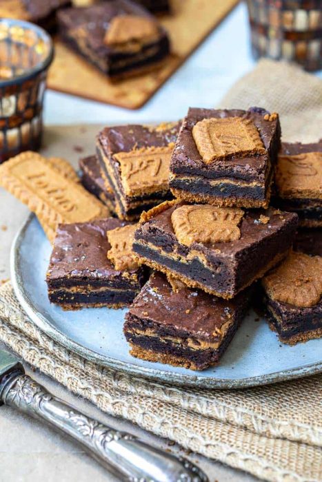 A plate of chocolate brownies topped with Biscoff cookies, with extra cookies and brownies in the background—perfect inspiration for the Best Brownie Recipes for Every Occasion.
