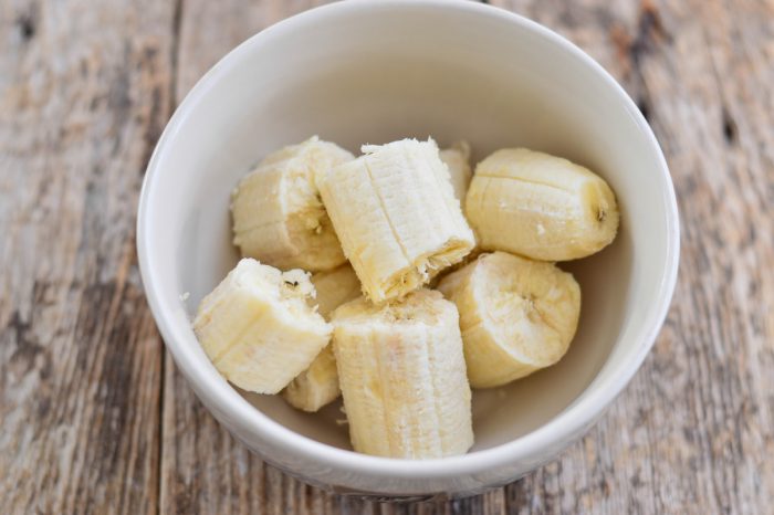 bananas and PB2 A white bowl containing several pieces of peeled, sliced banana is placed on a wooden surface—perfect as part of HEALTHY LUNCHES.