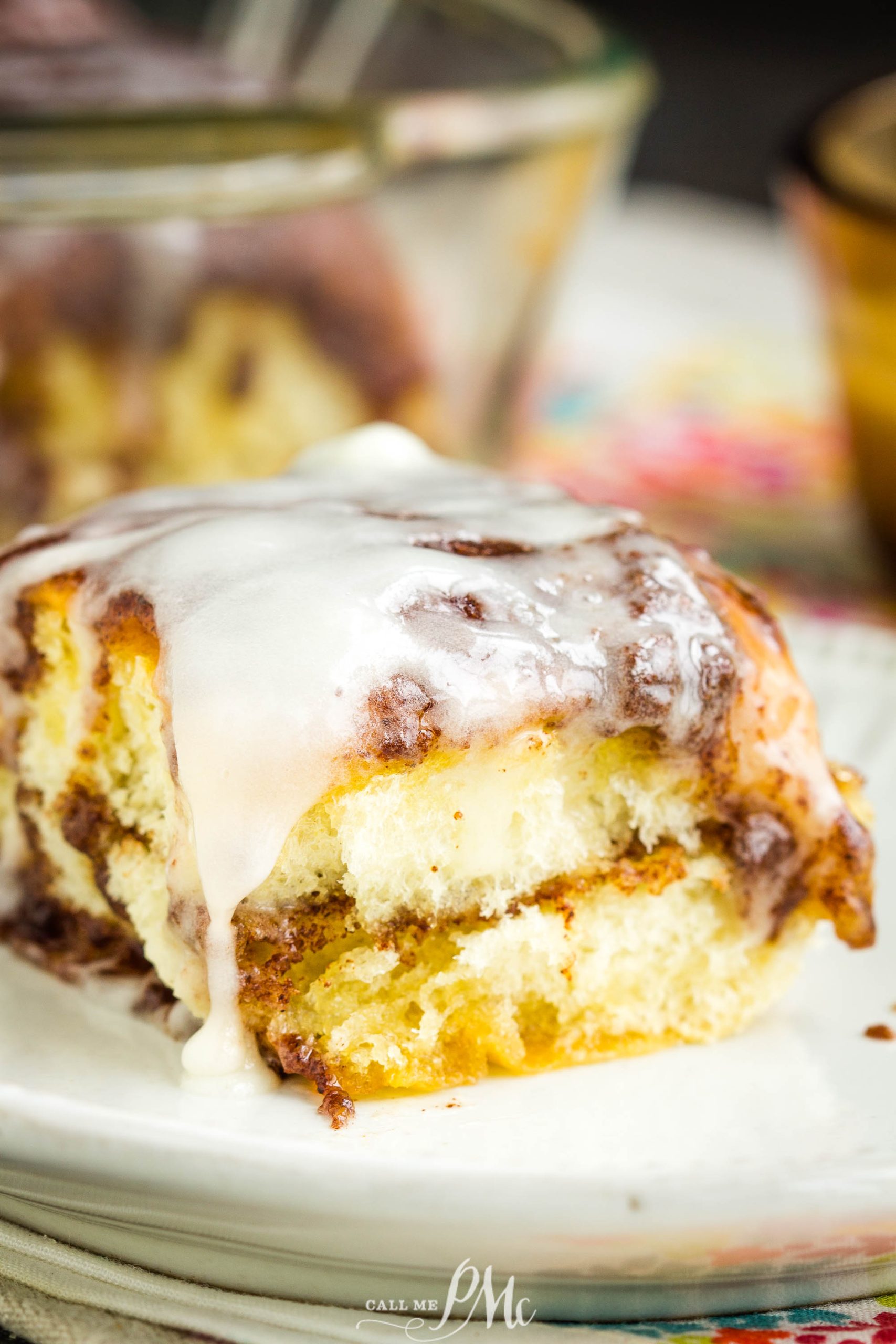 A close-up of Quick Cinnamon Hawaiian Rolls topped with white icing, served on a white plate.