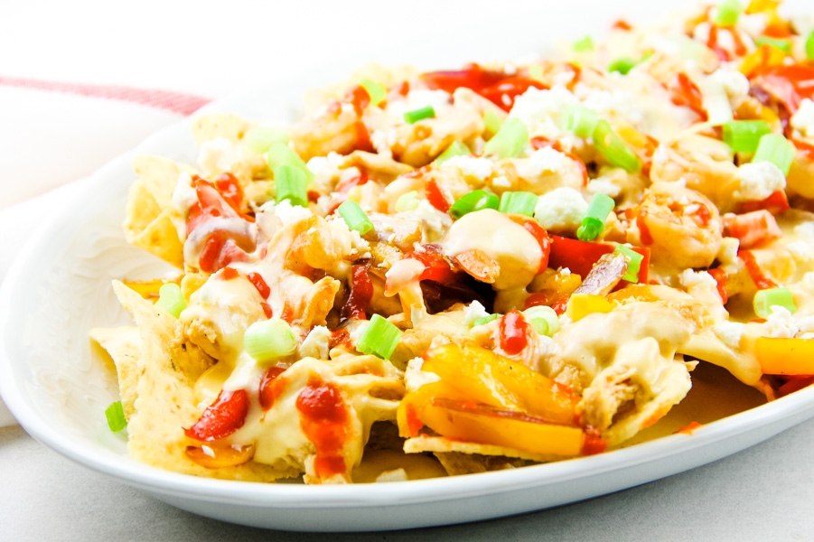 Chicken Shrimp Fajita Nachos are delicious when layered with all the good stuff chicken, shrimp, peppers, onions, and cheese. #chicken #shrimp #fajita #nachos White plate full of cheesy vegetables