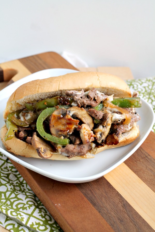 This Grand Escape Steak Sandwich has thinly sliced beef is cooked to perfection, melty cheese, peppers, onions, seasonings, and sauces. #steak #sandwich #recipe #beef #phillycheesesteak #cheesy Steak Sandwich