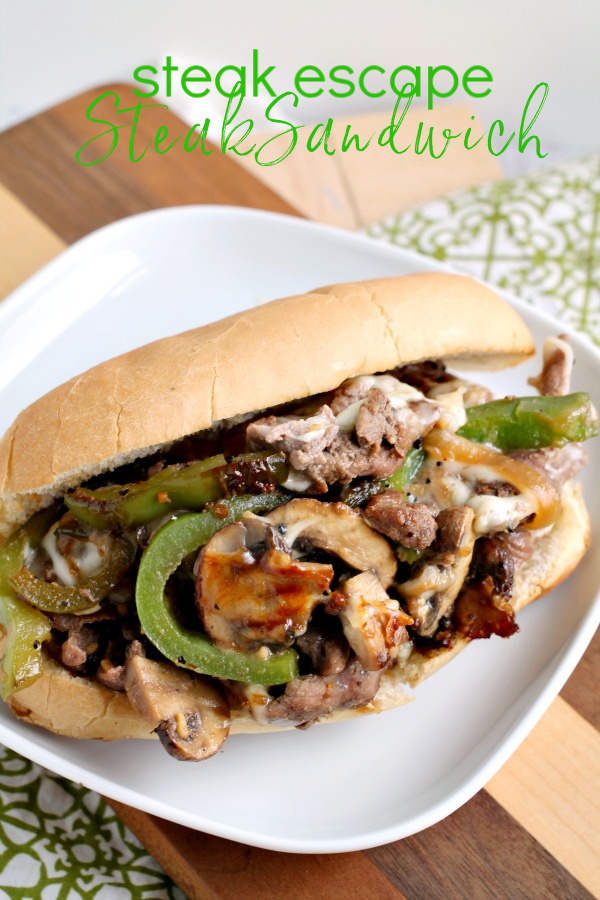 This Grand Escape Steak Sandwich has thinly sliced beef is cooked to perfection, melty cheese, peppers, onions, seasonings, and sauces. #steak #sandwich #recipe #beef #phillycheesesteak #cheesy