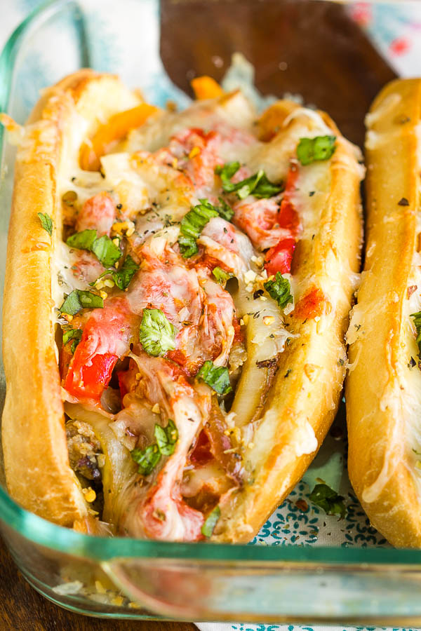 Sausage Pepper Onion Hoagies a delicious, hearty 30-minute meal! Italian sausage, onions, peppers, tomato sauce, and lots of mozzarella make this sandwich a family favorite. #sausage #sandwich #Italian #hoagie #pizza #pizzasandwich #pizzahoagie #pepeprs #onions #Italiansausage #easy #20minute #recipe Stuffed bun in a casserole dish.
