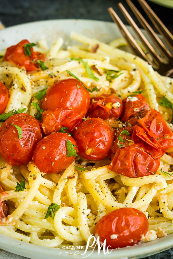 A plate of blistered tomato ricotta pasta, tossed with cherry tomatoes and herbs, garnished with black pepper.
