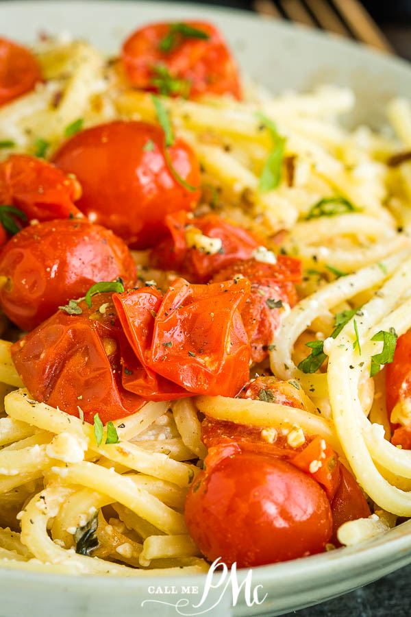 A plate of blistered tomato ricotta pasta, tossed with cherry tomatoes and herbs, garnished with black pepper.