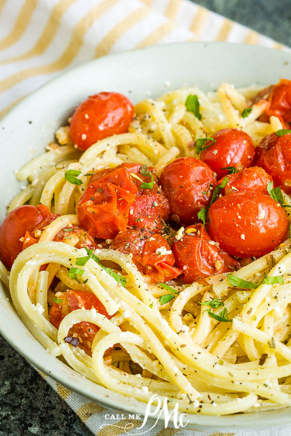 A plate of noodles, tossed with cherry tomatoes and herbs, garnished with black pepper.
