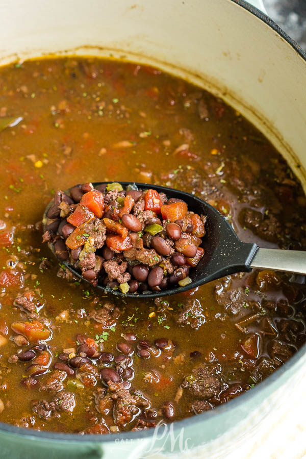 cooked black beans in a Dutch oven A Dutch oven full of stew with a spoonful.