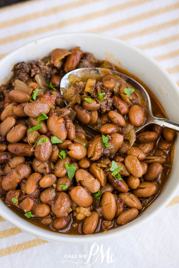 Cooked pinto beans in a bowl with cilantro Slow Cooker Pinto Beans and Sausage in a bowl with a spoon garnished with cilantro