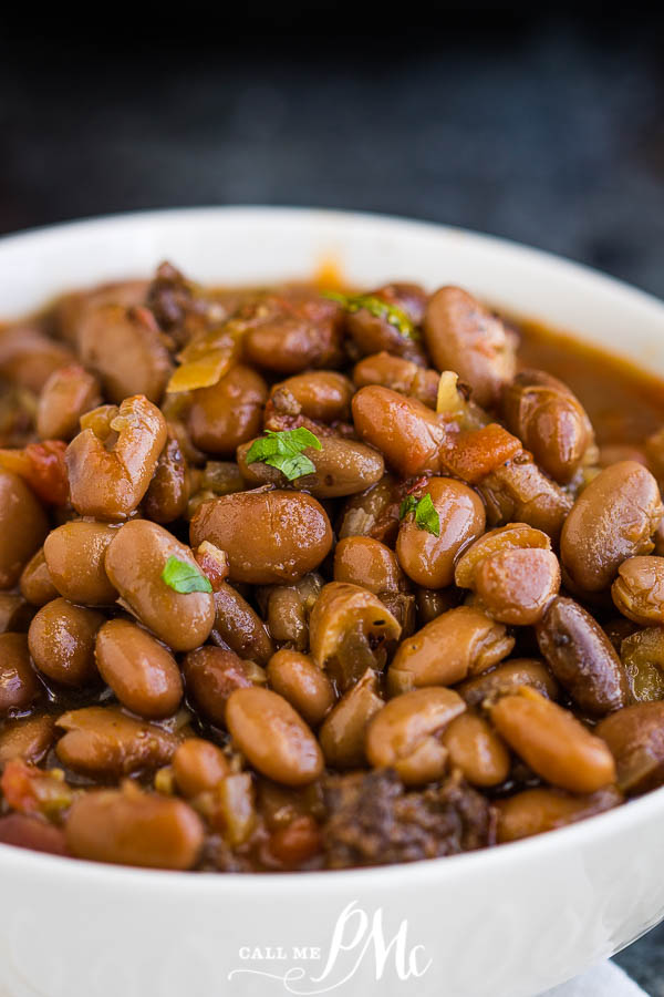 A bowl of beans with pieces of vegetables, garnished with chopped herbs.
