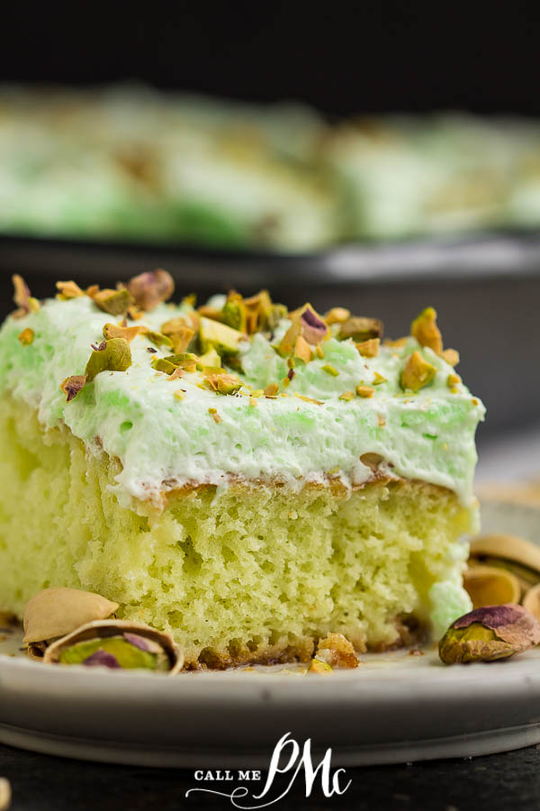 Whipped Cream Frosted Pistachio Poke Cake aka Watergate Cake is a vintage dessert with cake mix & instant pudding. Easy to make dessert. #pistachiocake #cake #recipe #dessert #easy #moist #callmepmc square green cake with green frosting and nuts