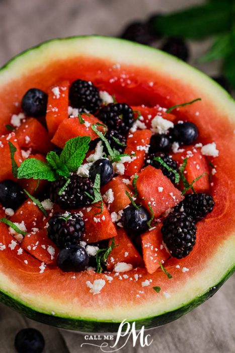 A hollowed-out fruit half filled with cubed berries and garnished with mint leaves.