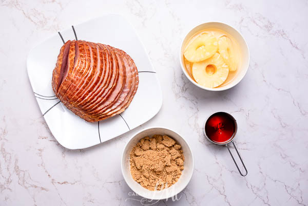 ham ingredients An Instant Pot Pineapple Brown Sugar Ham serves as the centerpiece on a plate, accompanied by a small bowl of cinnamon.