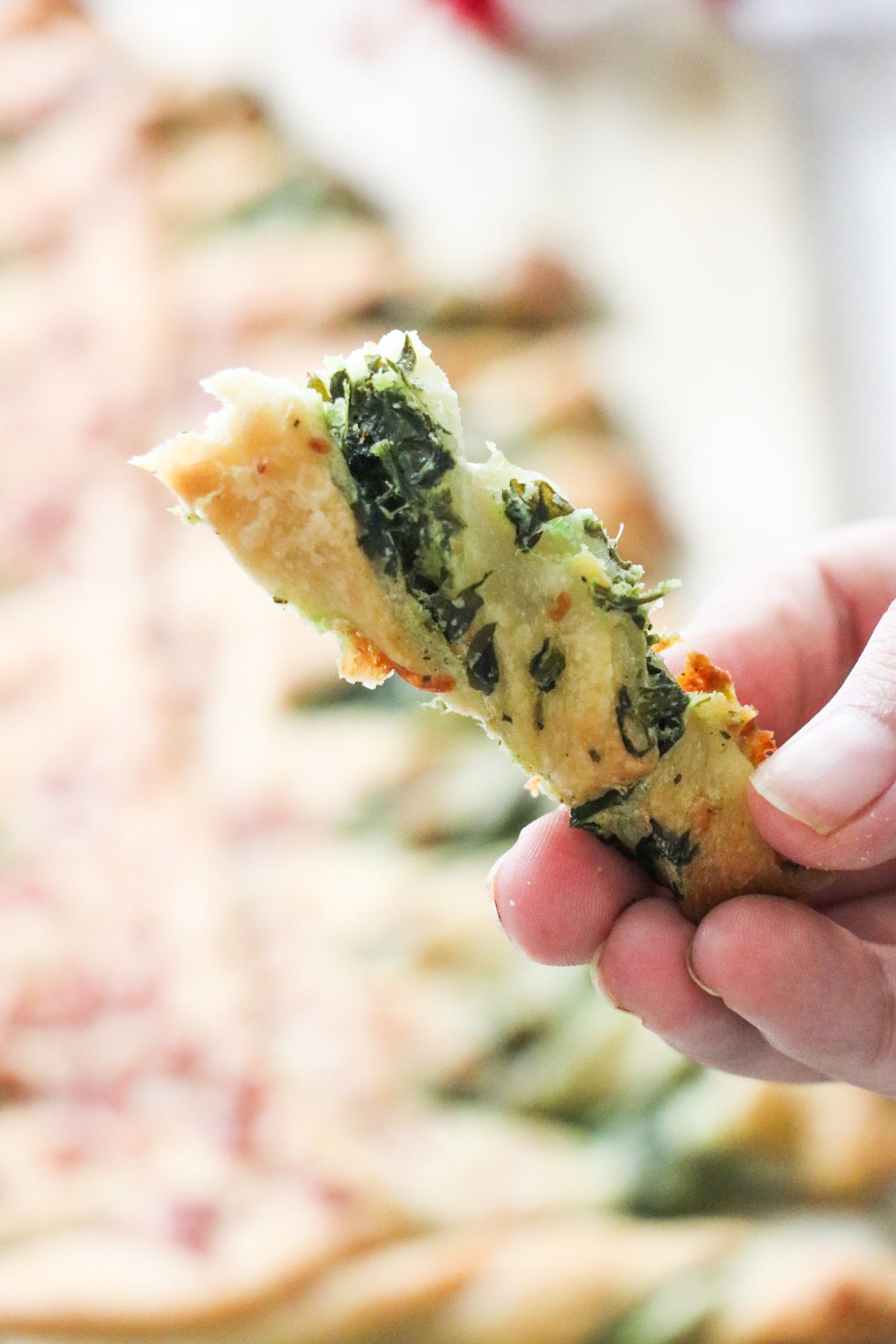hand holding a spinach dip breadstick.