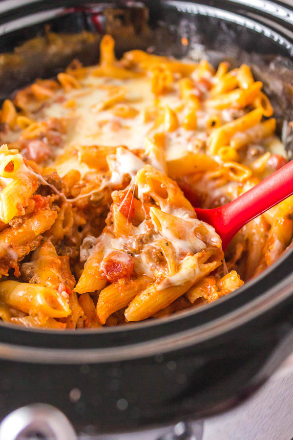 A cheesy crock pot filled with penne and sauce.