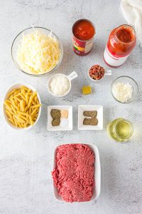 The Slow Cooker Cheesy Penne ingredients for a meatball pizza are laid out on a table.