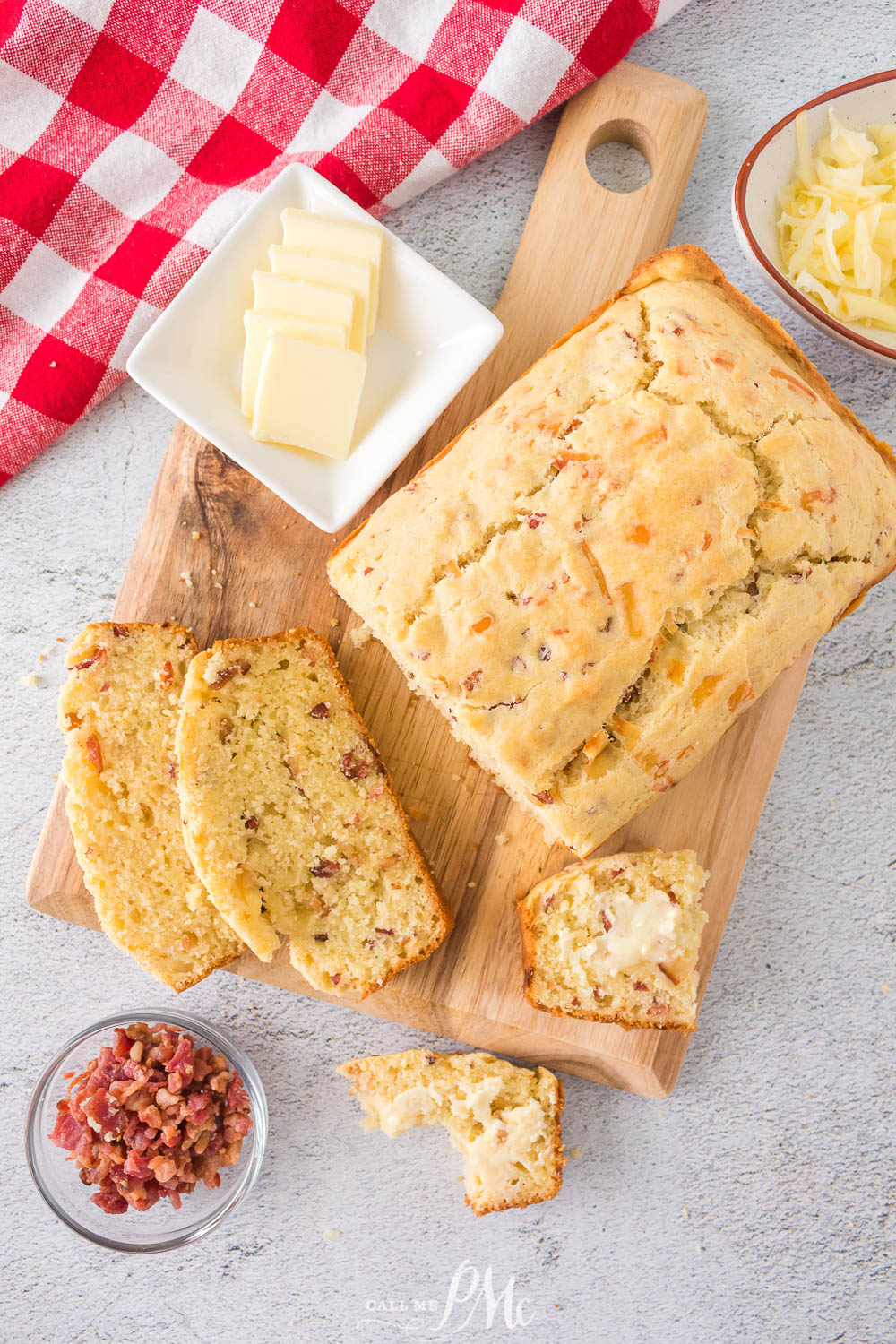 A quick bread with cheddar cheese and bacon on a cutting board.