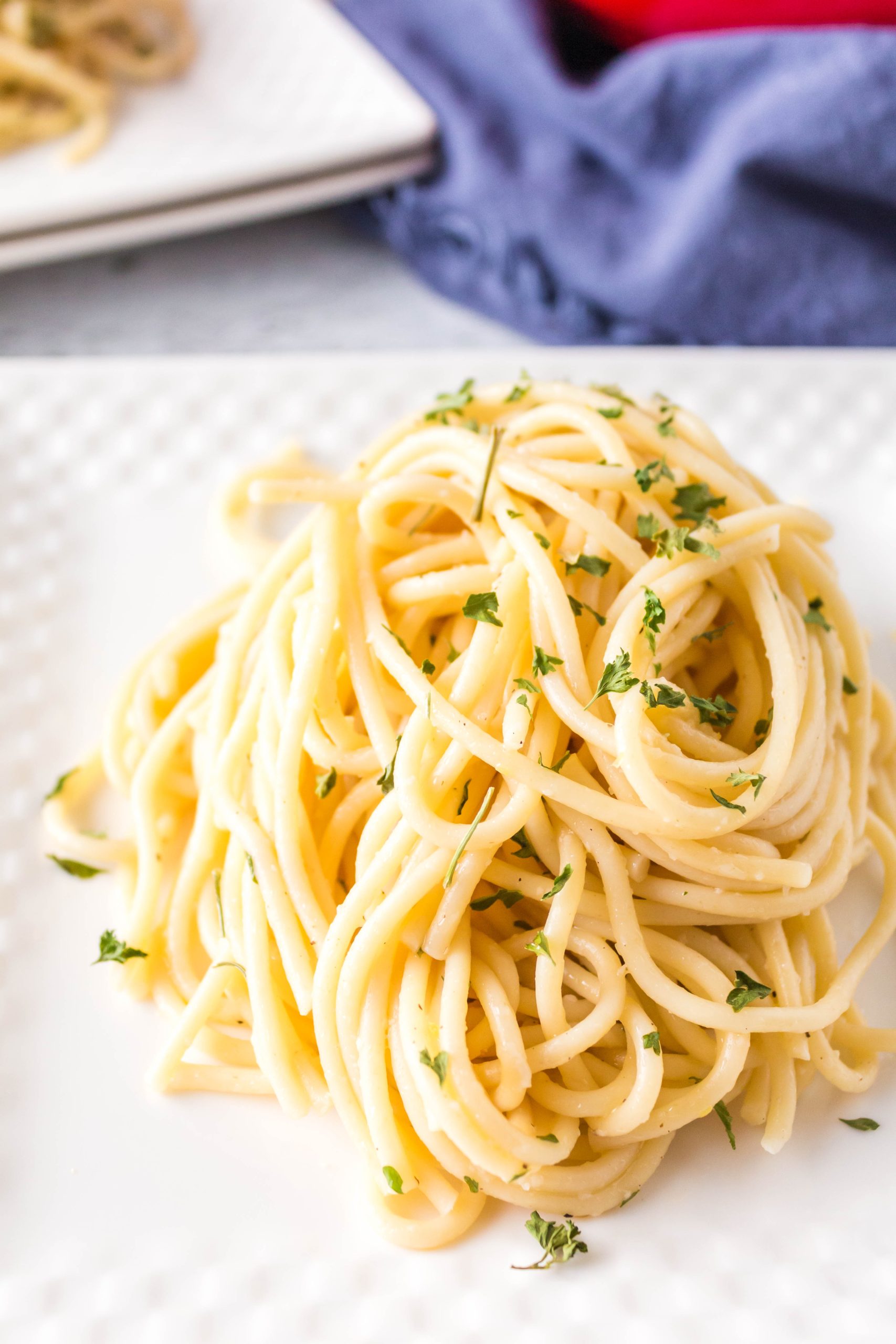 A plate of lemon garlic butter pasta with herbs on it.