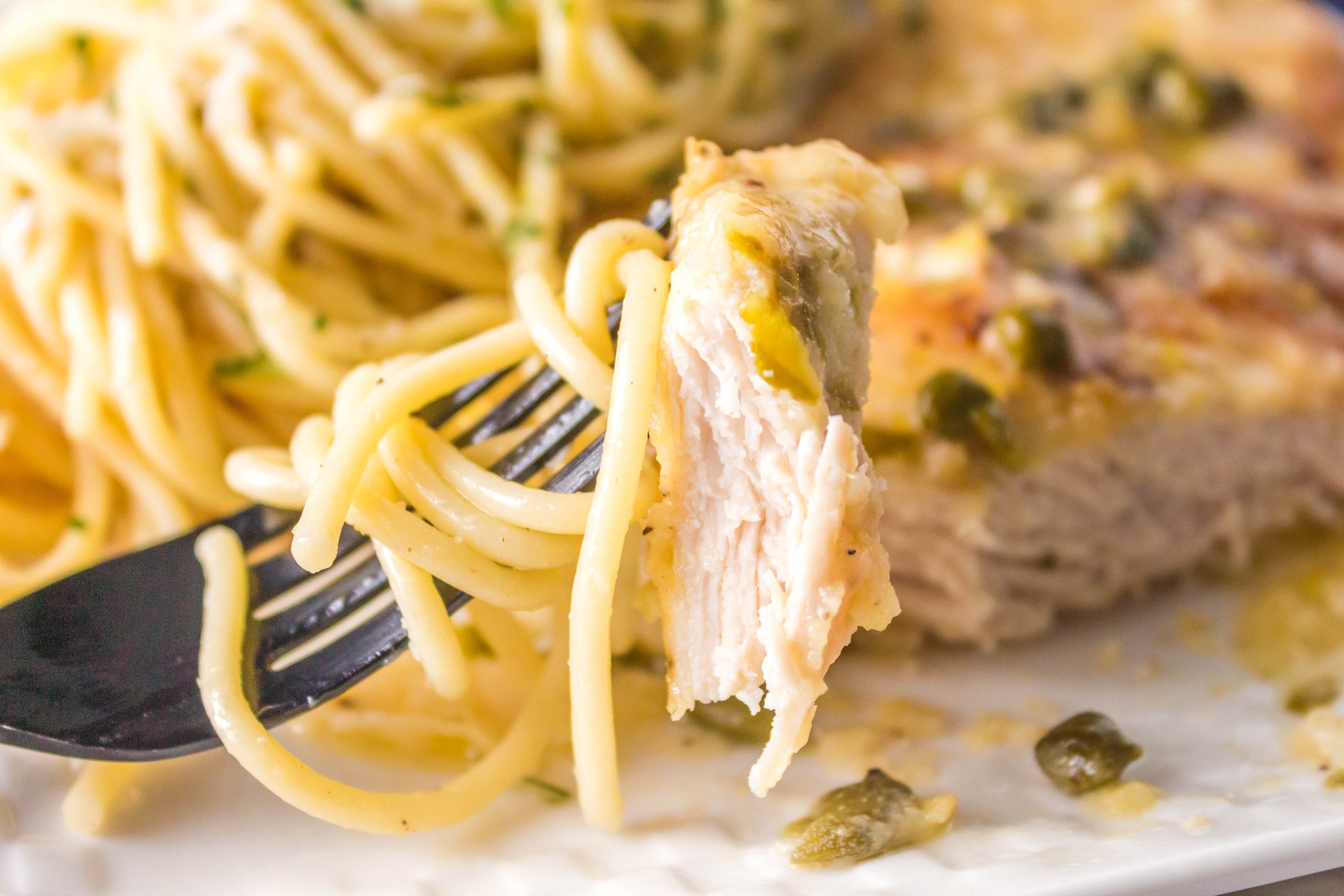 Bite of Chicken breast and pasta on a fork.