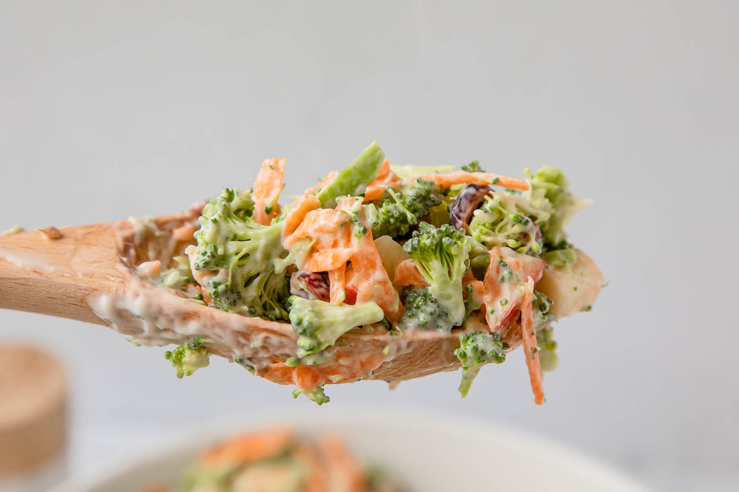 Quick and Creamy Broccoli Apple Salad Recipe Broccoli and shredded carrots on a mixing spoon.