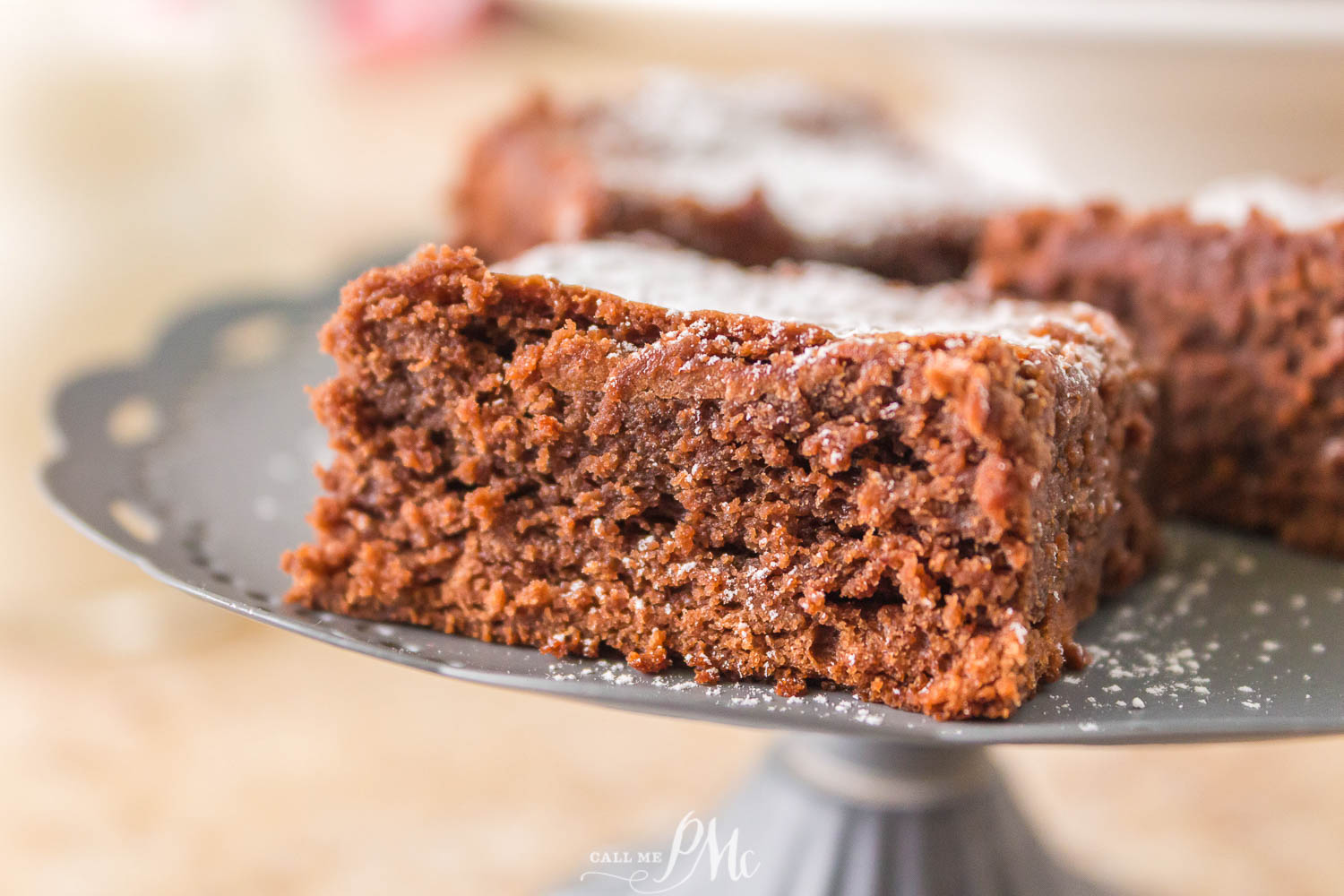Gooey Condensed Milk Brownies One light chocolate Brownies on a cake plate.