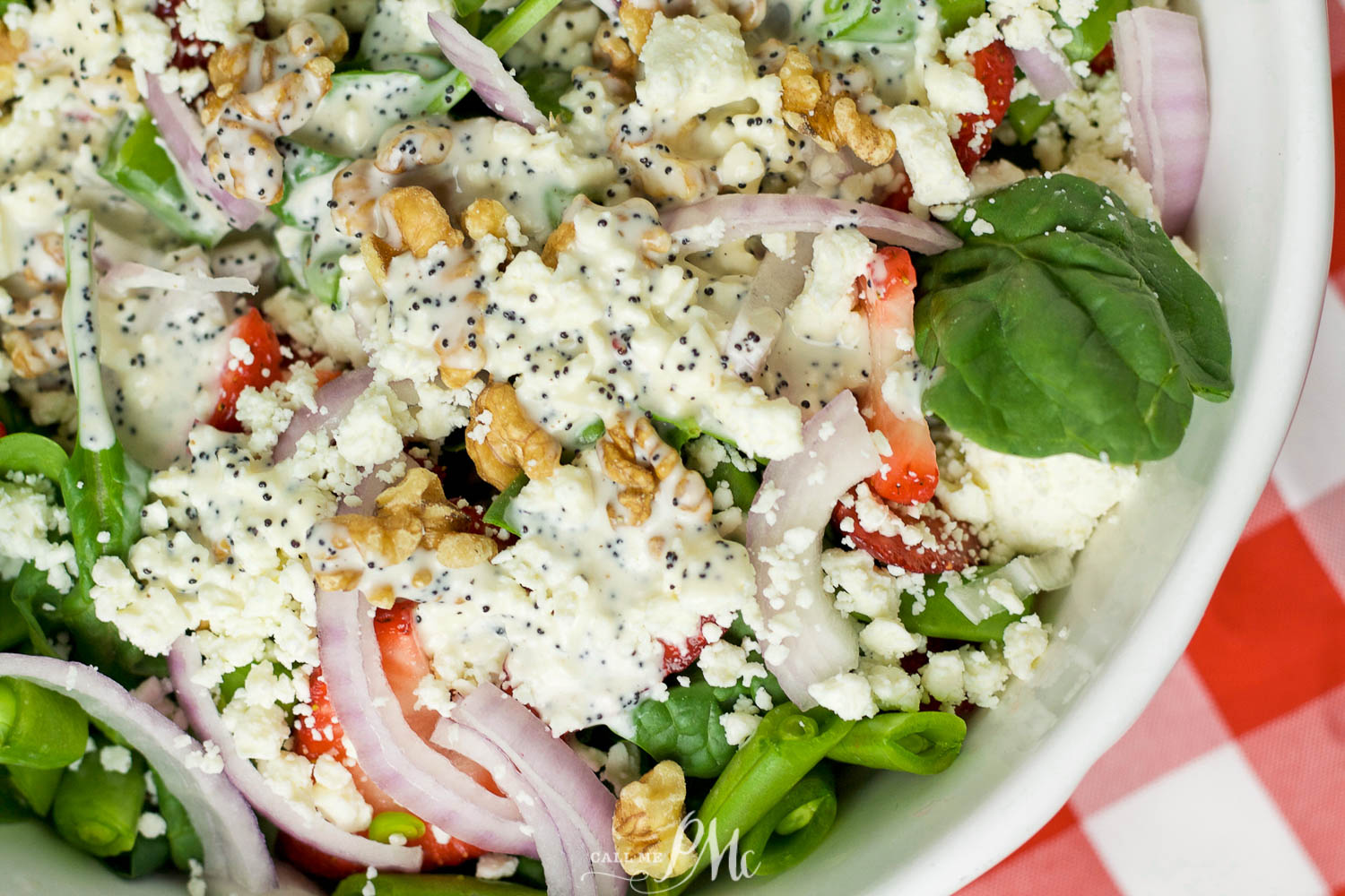 Large salad with spinach, strawberry slices, red onion, and poppy seed dressing.