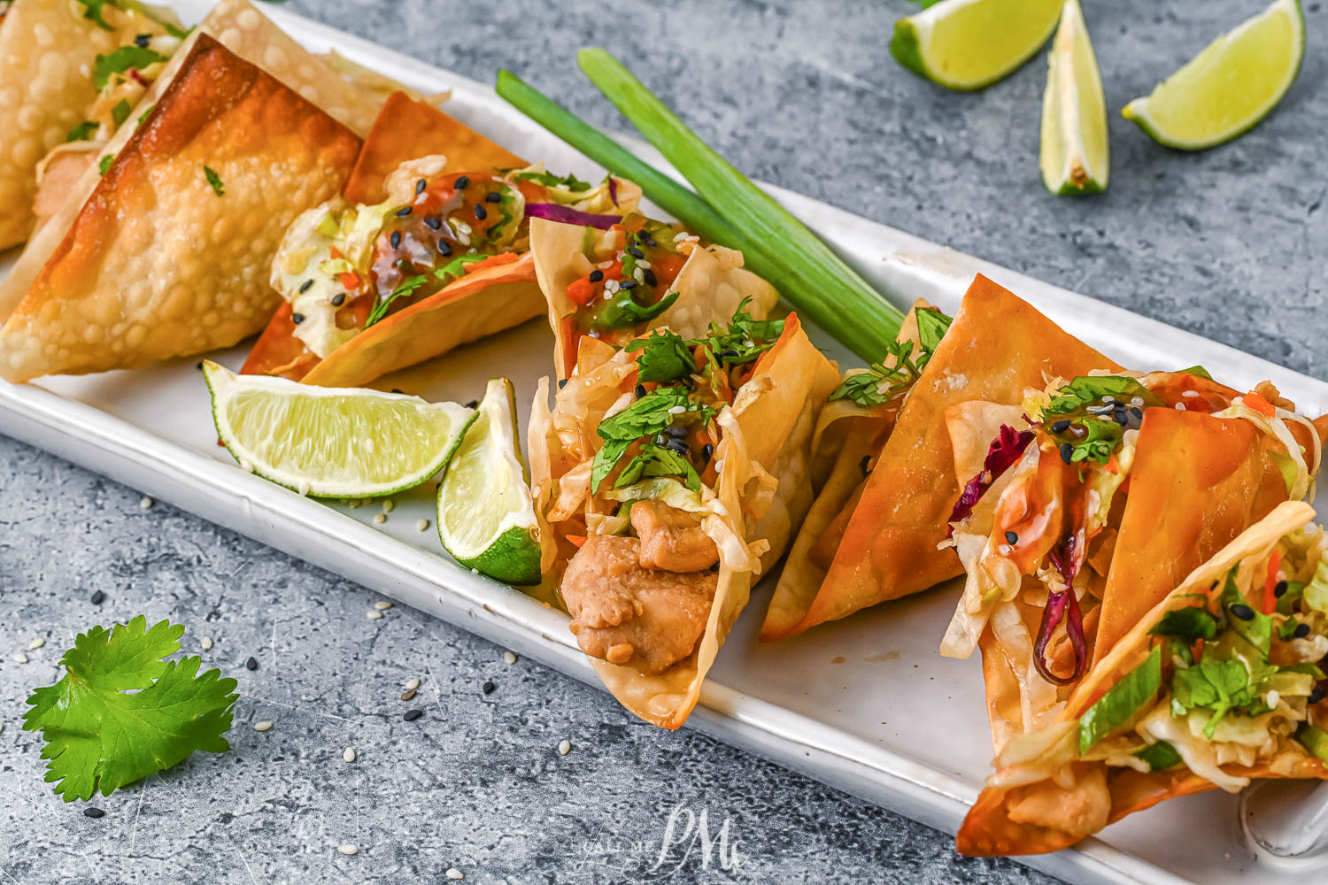 Long tray lined with wonton tacos and lime wedges.