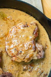 A peppercorn pork chop with creamy onion gravy sizzles perfectly in a cast iron skillet.
