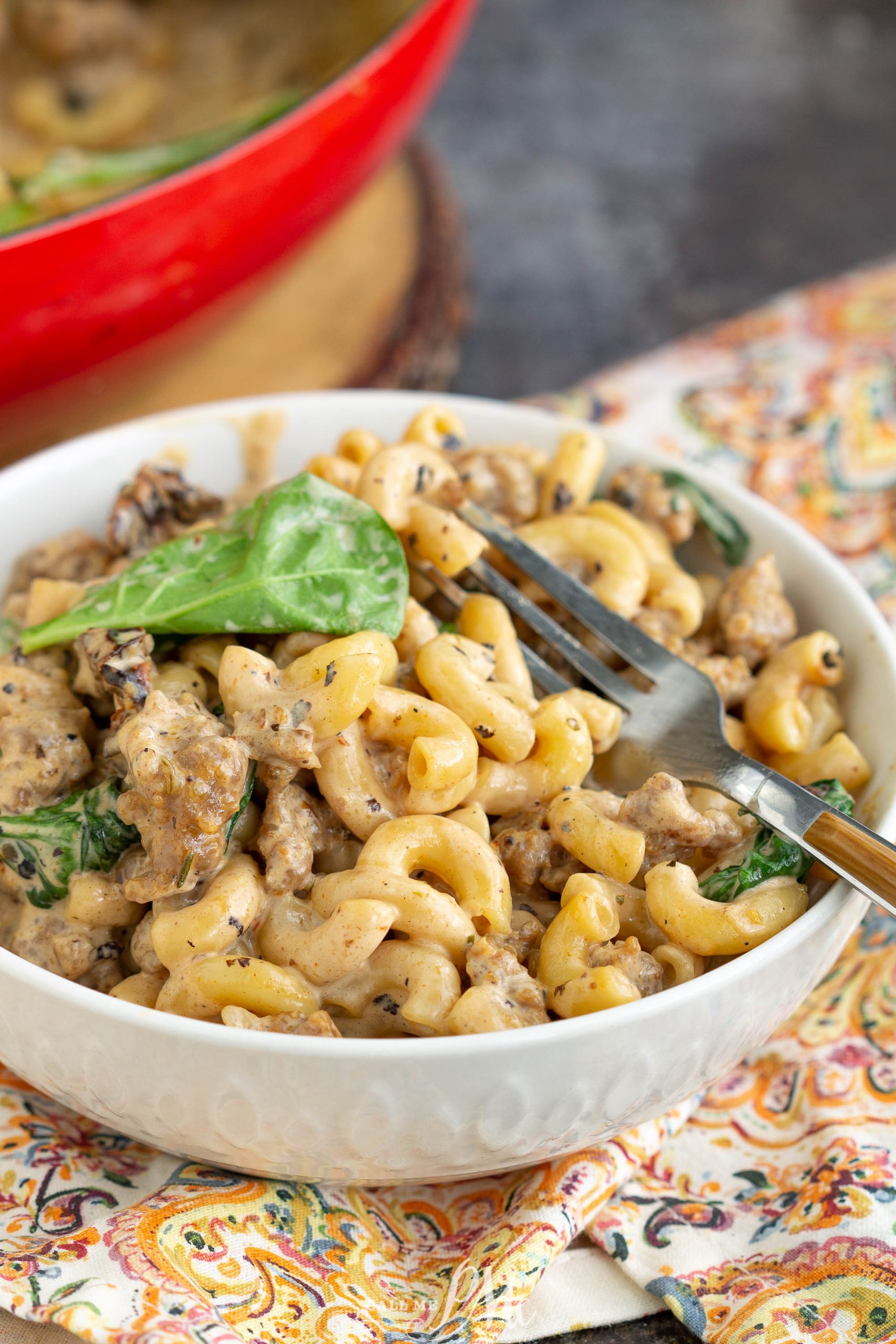 An Italian bowl of pasta with meat and spinach.