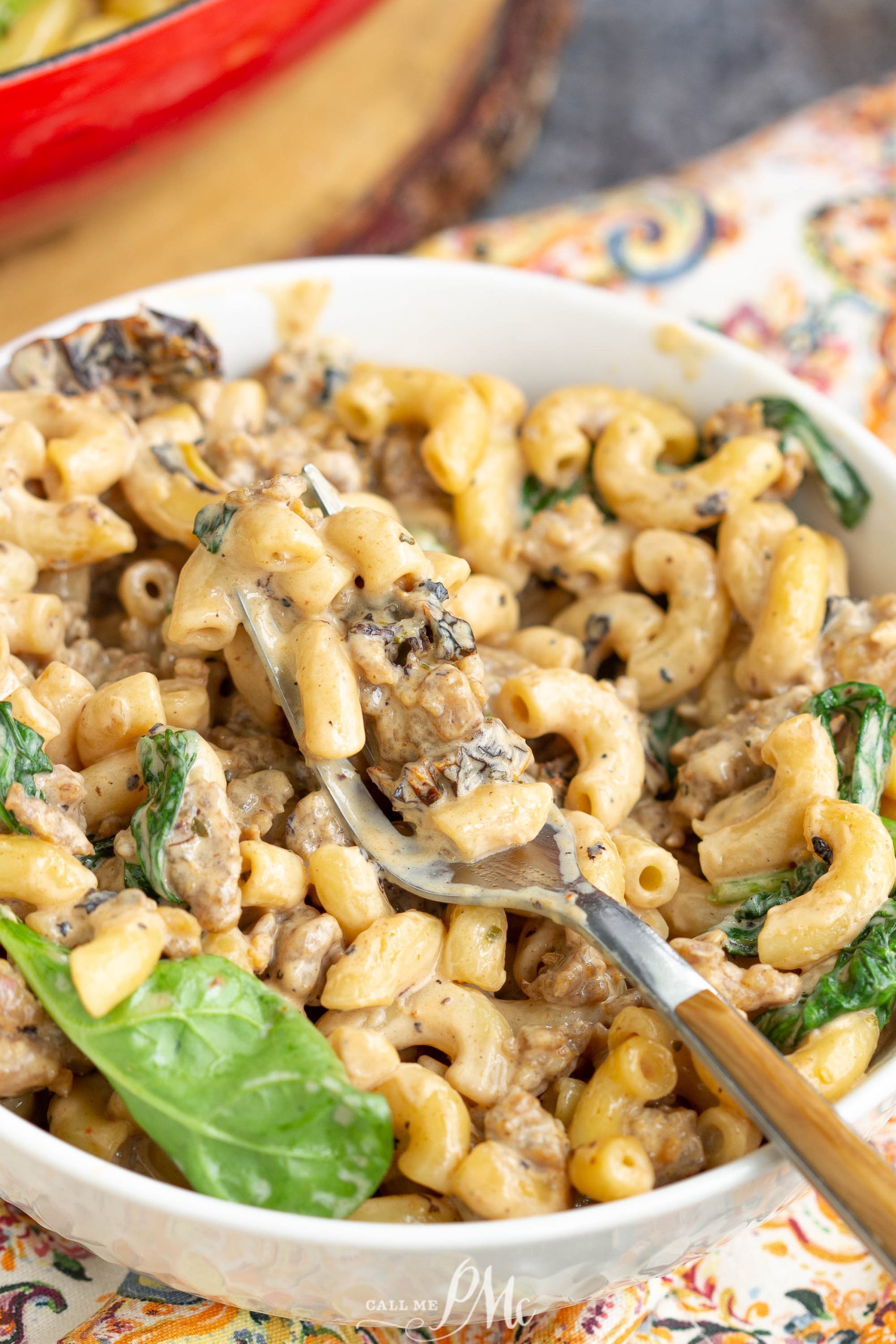 A bowl of Italian sausage pasta with a fork.