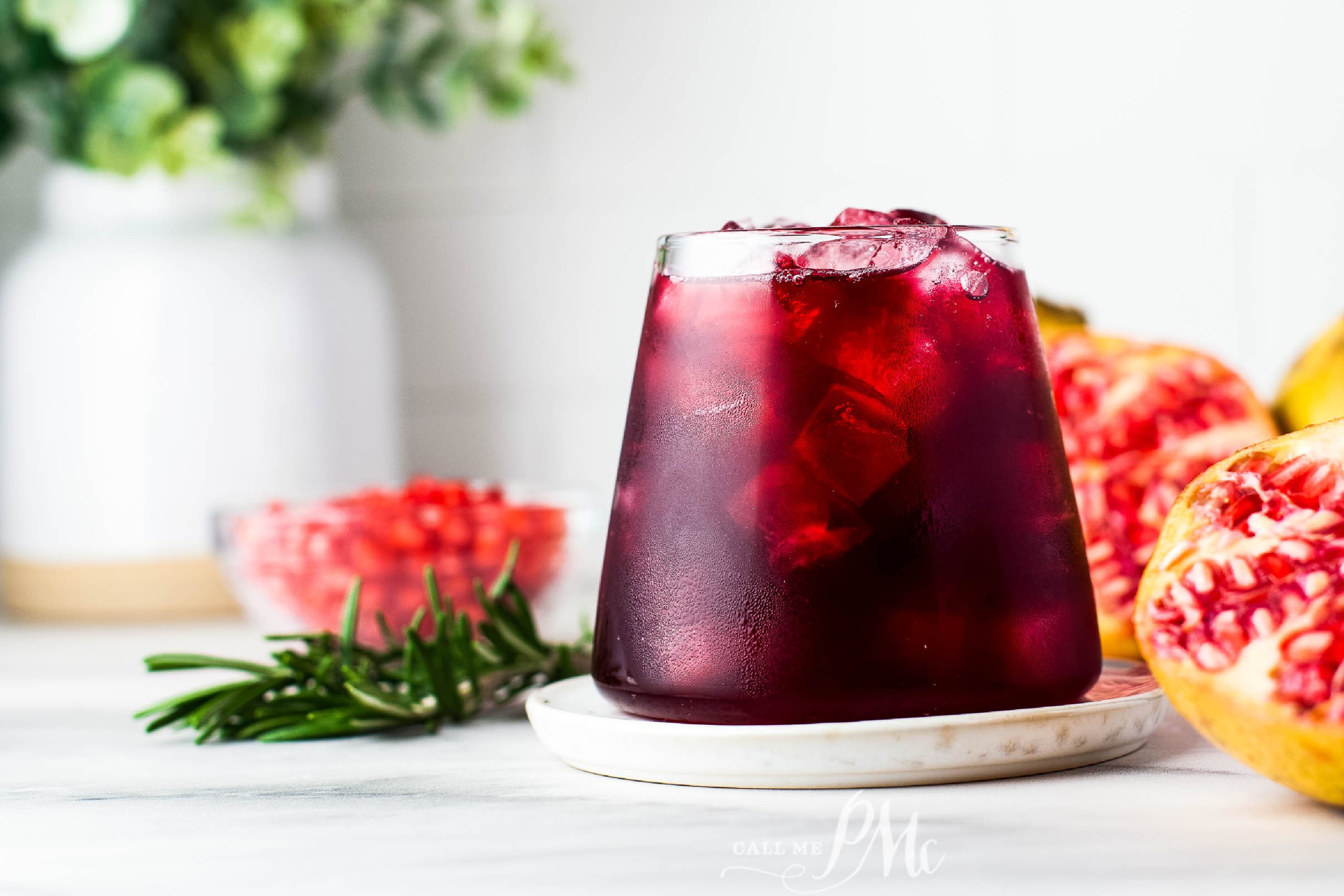 A refreshing pomegranate-infused drink garnished with rosemary and pomegranate seeds.