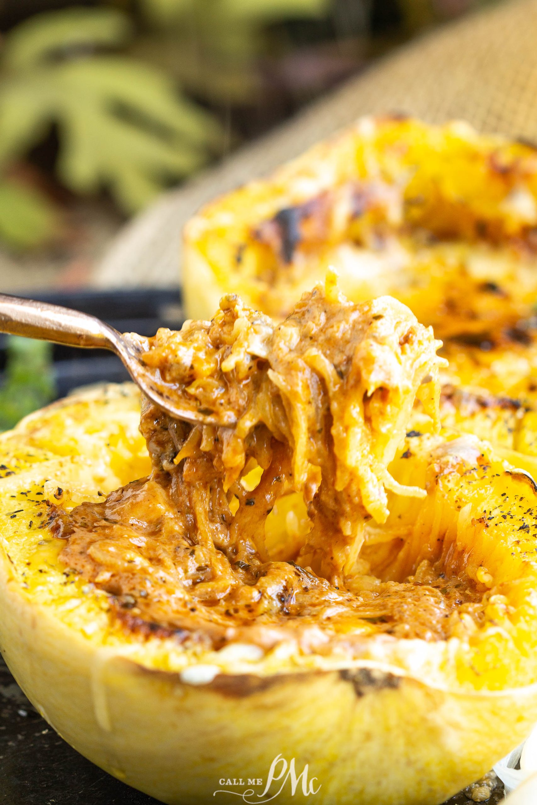 A spoon is used to take out vodka sauce from inside a spaghetti squash boat.